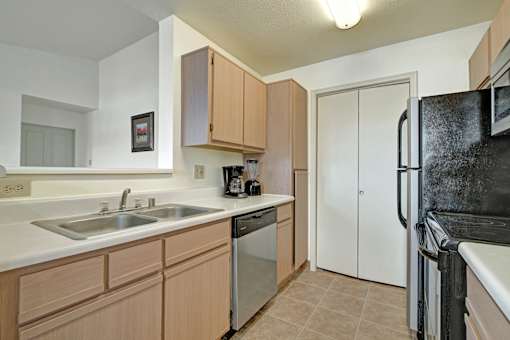 A kitchen with a black refrigerator and white countertops.