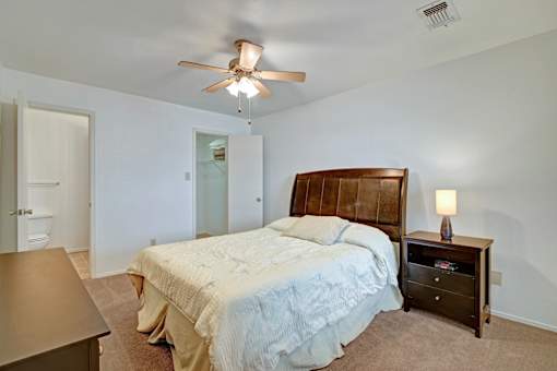 A bedroom with a bed, nightstand, and ceiling fan.