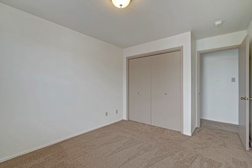 A room with a carpeted floor and two doors.