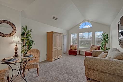 A living room with a glass table and chairs, a couch, and a cabinet.