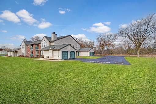 A large house with a green garage door sits in a grassy field.