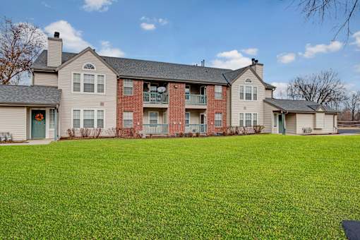A large grassy area in front of a two story apartment building.