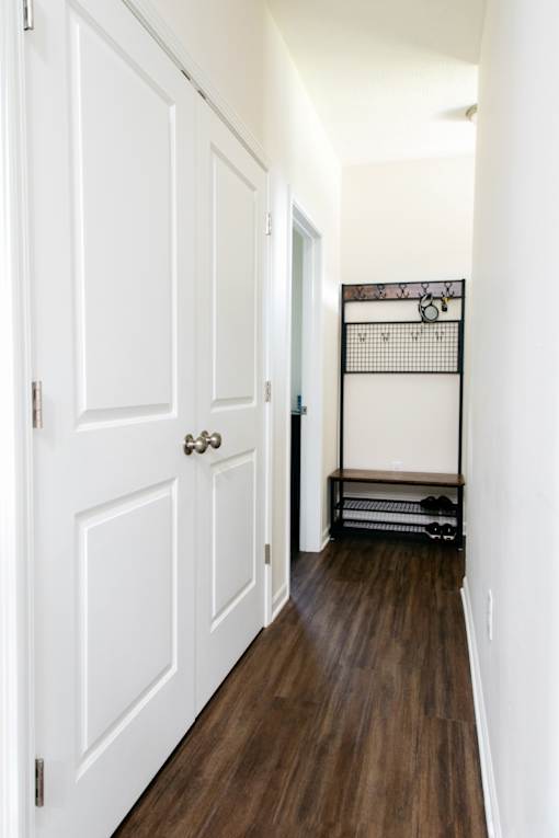 A hallway with a white door and a black rack on the wall.