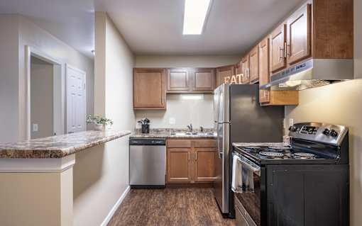 A kitchen with a black stove top oven and a refrigerator.