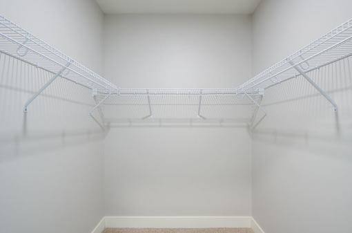 Empty white walk in closet with shelves.