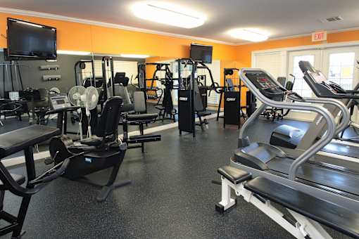 A gym with a variety of equipment including treadmills, weights, and exercise machines.