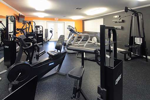 A gym with a variety of equipment including treadmills, weights, and exercise machines.