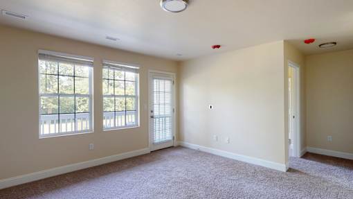 A room with a carpeted floor and a window with blinds.