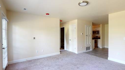A spacious living room with a carpeted floor and white walls.