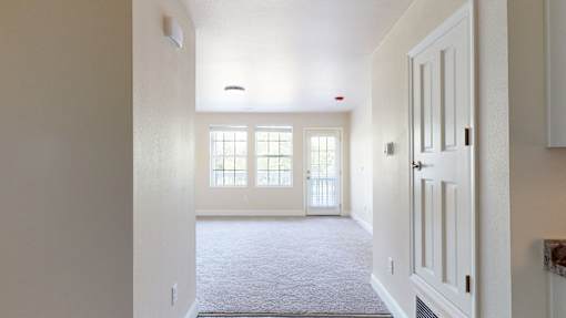 A hallway with a carpeted floor and white walls.