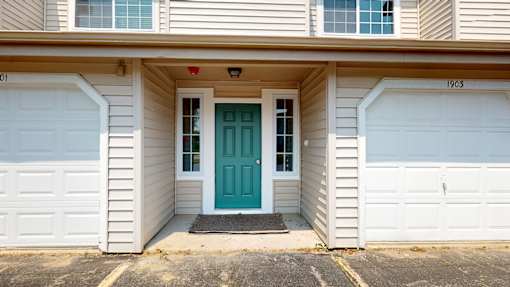 A house with a blue door and white garage doors.
