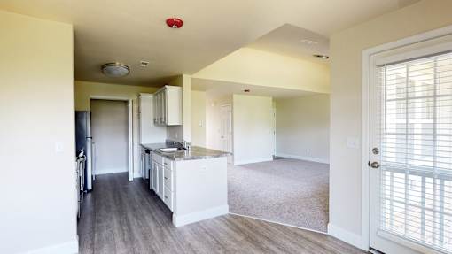 A kitchen with white cabinets and a countertop is visible from the living room.