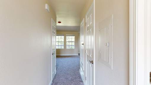 A long hallway with white walls and a carpeted floor.