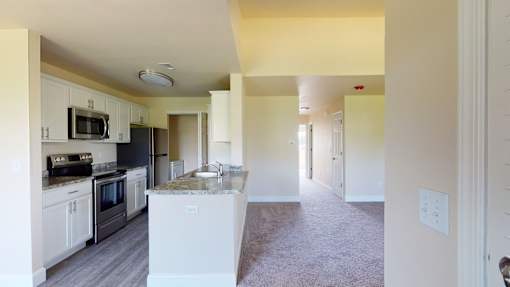 A kitchen with white cabinets and a black countertop.