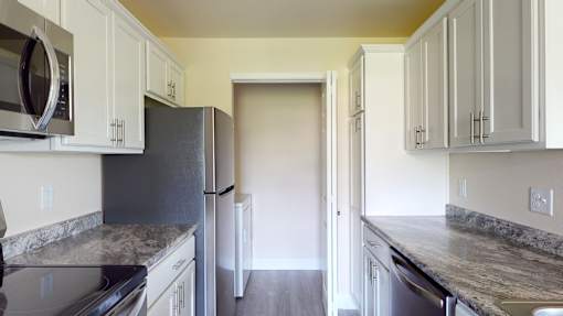A kitchen with white cabinets and granite countertops.