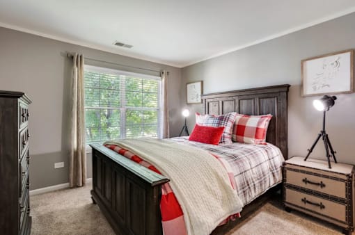 A bedroom with a large bed and a wooden dresser.