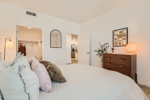 a bedroom with a large bed and a dresser with a mirror