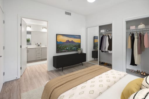 a bedroom with a bed and a bathroom with a closet and a tv