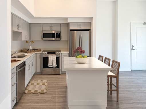 Modern open-concept kitchen with wood plank flooring, island, white cabinets and shaker cabinets.