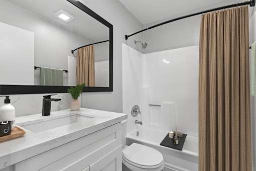 Beautiful updated bathroom in 1 Bed 1 Bath Azusa Gardens Apartment home with white shaker cabinets, quartz countertops, matte black finishes, and a large shower/tub