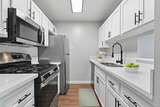 A modern kitchen with white cabinets and stainless steel appliances.