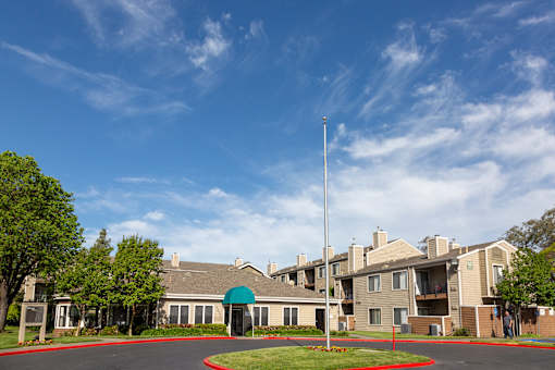Entrance to leasing office at California Place apartments surrounded by lush greenery and blue skies