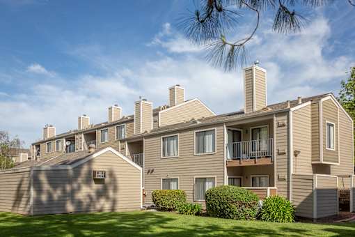 Charming exterior of California Place apartments with grass lined walkways and lush greenery, providing a beautiful and serene living experience!