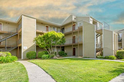 Charming exterior of California Place apartments with grass lined walkways and lush greenery, providing a beautiful and serene living experience!