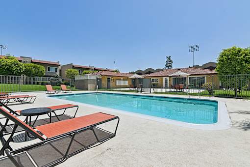 Luxurious swimming pool at Azusa Gardens surrounded by chaise loungers and lush greenery