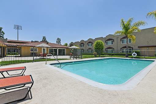 Luxurious swimming pool at Azusa Gardens surrounded by chaise loungers and lush greenery