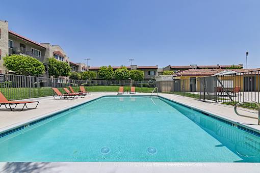 Luxurious swimming pool at Azusa Gardens surrounded by chaise loungers and lush greenery