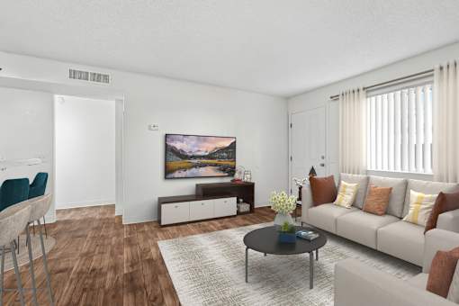 Living Room in 2 Bed 2 Bath Bent Tree Apartment with Large Windows allowing for gorgeous natural lighting, wood plank-style flooring, and view into dining nook & kitchen complete with bar top seating