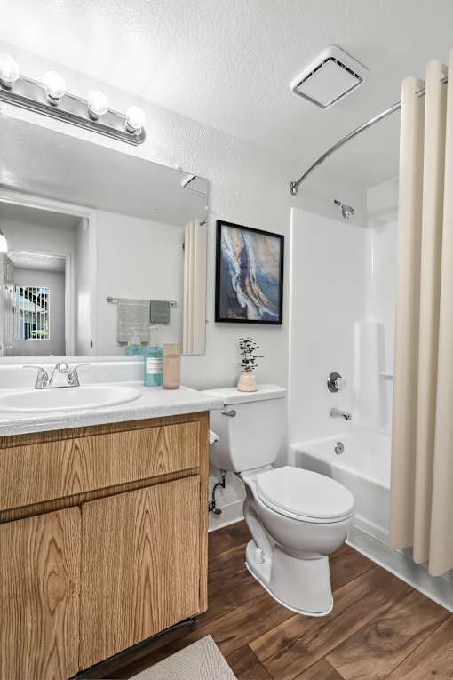 Bathroom 1 in 2 Bed 2 Bath Bent Tree Apartment home with wood plank-style flooring, a large vanity mirror and a shower/tub