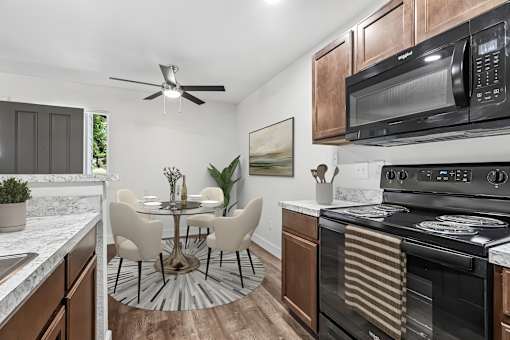 Kitchen in 2 Bedroom 1 Bath Option B Bent Tree Apartment with wood plank-style flooring, dark wood cabinets, black appliances, and modern marbled countertop.