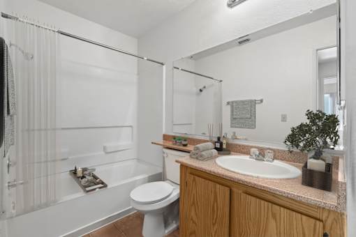 A white bathroom with a toilet, sink, and shower.