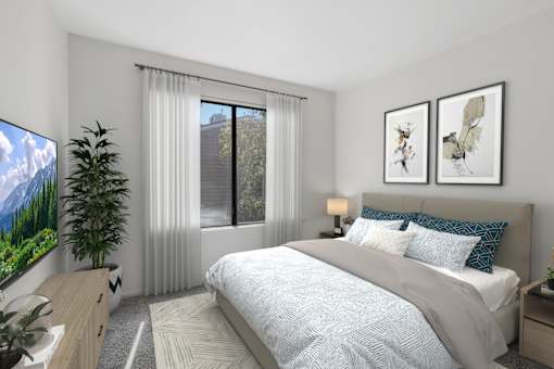 Bedroom in 1 Bed 1 Bath A California Place floor plan with plush carpeted flooring and a large window allowing for gorgeous natural light to filter through the room and views of the properties' lush greenery.