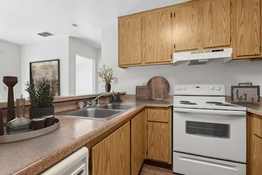 Kitchen in 1 Bed 1 Bath A California Place floor plan with light wood cabinets, white appliances, plenty of counter and storage space for all of your needs, and wood-style plank flooring