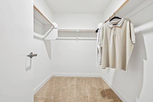 a spacious walk in closet with a white wall and a white closet door with a