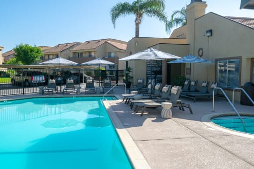a swimming pool with tables and umbrellas in front of leasing office