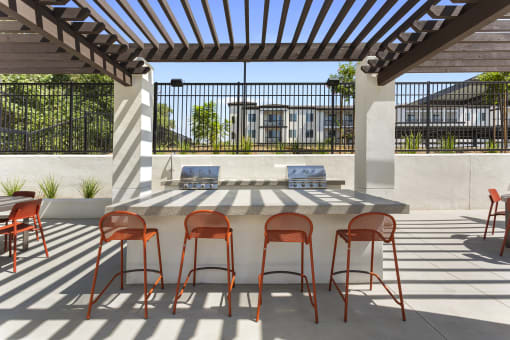 a patio with a bar with chairs and a table