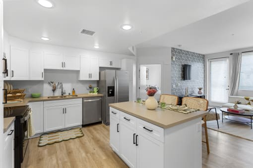 an open kitchen and living room with white cabinets and stainless steel appliances