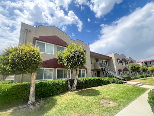 Exterior of Azusa Gardens Apartment Homes with grass-lined walkways and plenty of lush greenery