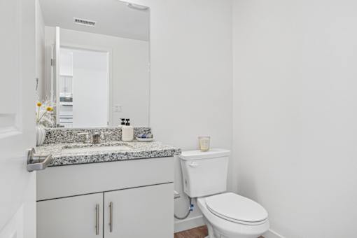 Bathroom with granite vanity and white cabinetry at Altitude Apartments, Moreno Valley, CA