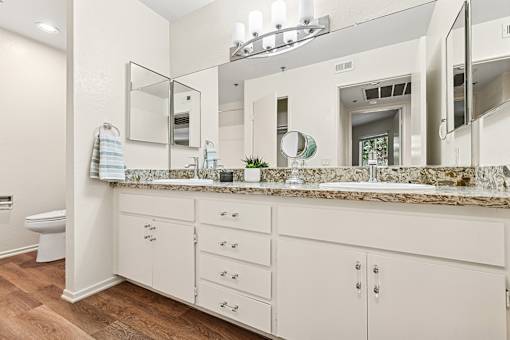Oversized bathroom in Cielo apartment home with plank flooring, dual sink vanity, plenty of storage space and separate room with shower/tub and toilet