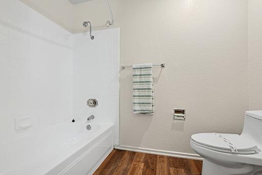 Bathroom in Cielo apartment home with plank flooring and a shower/tub