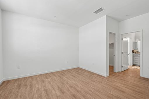 Empty bedroom with laminate flooring and walk-in closet at Altitude Apartments, California