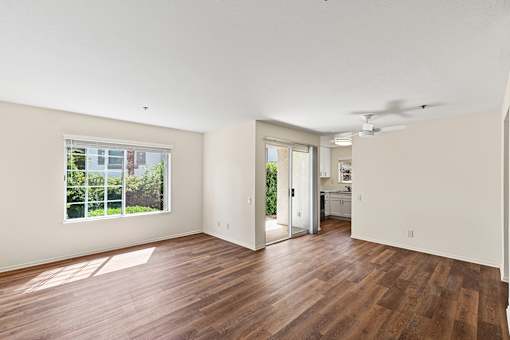 Open concept Cielo apartment with plank flooring, large windows, sliding doors leading to private patio, dining area and kitchen.