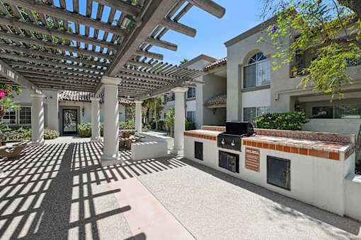 A patio with a white pergola and a white bench with a red tile back.