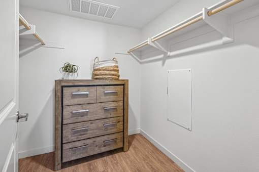 Walk-in closet with dresser and overhead shelving at Altitude Apartments, Moreno Valley, California