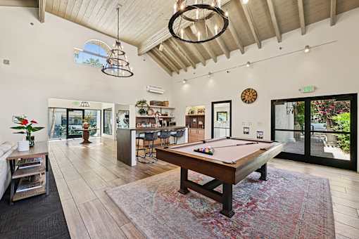 A pool table is in the middle of a room with a wooden floor.